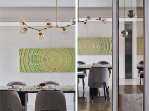 Modern dining room with a glass and metal chandelier and a circular green and yellow artwork.