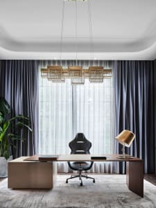 A modern office space featuring minimalist design with wooden desk, leather office chair, and glass windows with gray curtain