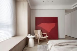 Contemporary minimalist bedroom featuring a red abstract canvas, woven chair, and white furniture.
