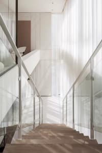 A modern minimalist staircase with glass railings.