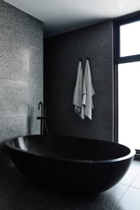 Modern minimalist bathroom featuring a sleek black bathtub made of marble.
