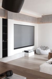 A minimalist home theater with a large projection screen, projector, and comfortable seating.