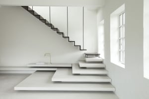 Modern minimalist interior design featuring a concrete staircase with floating steps and a simple, elegant lamp.