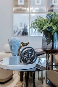 A modern interior space featuring metallic elements, glass vases, and wooden sculptures.