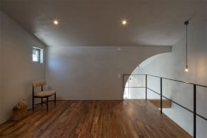 Minimalist living room with wooden floor and window, featuring natural light.