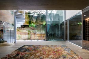 A modern interior space with a wooden floor and natural light streaming through glass walls.