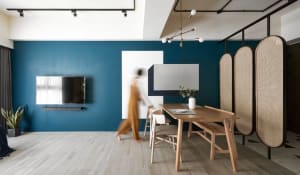 A modern living room with wood accents, a blue accent wall, and white geometric shapes.