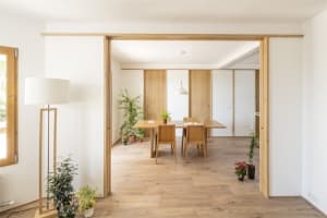Minimalist dining room with wooden furniture and green plants.