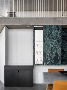 A modern kitchen featuring black marble cabinets, concrete countertops, and black metallic accents.