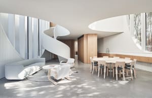 A modern residential living room with a white concrete floor and a white spiral staircase leading to another level.