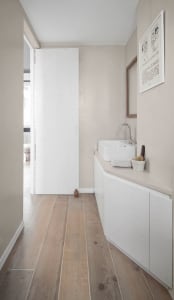 Modern minimalist bathroom with light wooden flooring tiles and a white, white basin on a concrete countertop.