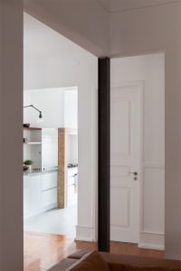 A minimalist kitchen with white flooring, showcasing sleek white cabinetry and modern design elements.