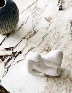 A minimalist interior design showcases a marble terrazzo countertop with a terrazzo figurine and vase.