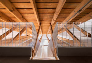 A minimalist staircase featuring wooden beams and metal railings viewed from above.