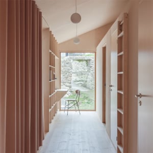 A minimalist interior with wooden shelves, stone walls, and a glass window.