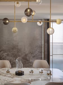 Modern dining room featuring marble table, glass light fixtures, and brass accents.