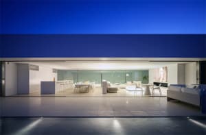 Modern living room with white furniture, floor-to-ceiling windows, and minimalistic design.