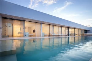 Modern exterior with glass walls and a concrete poolside lounge area.