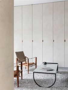 Modern minimalist living room featuring wood, leather, and marble accents.
