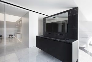 Modern, minimalist bathroom featuring black marble sink and white marble flooring.
