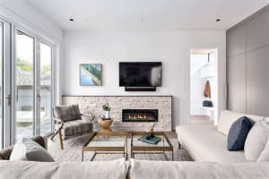 Modern living room featuring a comfortable seating area, a cozy fireplace, and a flat-screen TV on a white wall.