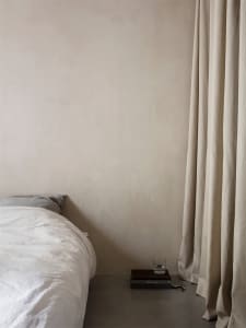 A minimalist bedroom with neutral tones and a bed.