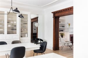 A modern white interior space featuring a white cabinet, black lighting, and wooden floor.