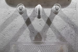Concrete water faucet and sink in an industrial-style bathroom