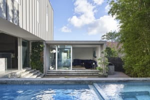 A modern exterior residential living space featuring glass and concrete materials.
