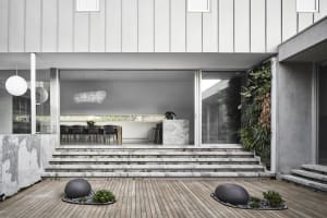 Modern residential interior featuring a concrete courtyard with steps and a wooden deck.