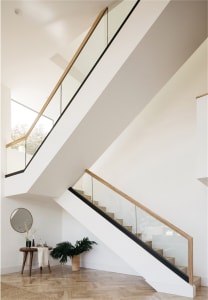 Modern staircase design featuring concrete steps, glass balustrades, and wooden railings.