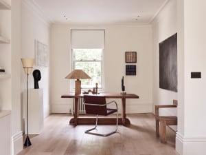 Minimalist home office featuring a wooden desk, leather chair, and various artworks.