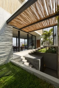 A modern house with a concrete exterior, featuring a layered wooden roof structure.