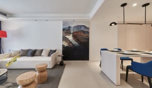 Modern living room with neutral-tones color palette, featuring a white sofa adorned with various cushions, a wooden stool, a 