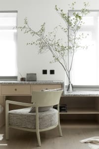 A modern home office featuring a wooden chair with a textured seat, a wooden desk with a terrazzo countertop, and a terrazzo 