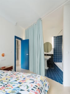 Modern minimalist bedroom with blue curtains and tile flooring.