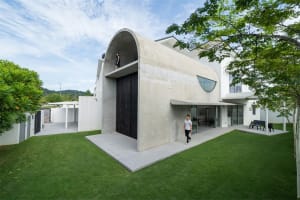 A modern residential exterior with a concrete façade and circular window.