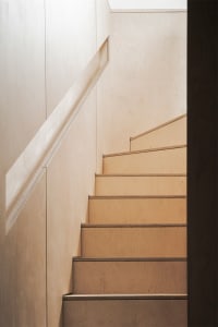 Modern wooden staircase with sleek, straight lines and light-colored wood finish.