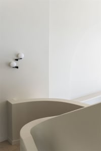 Modern, minimalist bathroom with smooth, white concrete walls and minimalist light fixtures.