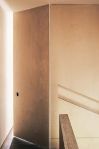A minimalist interior with a wooden staircase.
