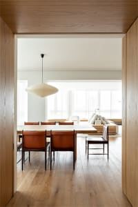 A modern dining room featuring a wooden table surrounded by leather chairs under a white ceiling light.