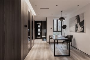 A minimalist workspace featuring a wooden table, glass windows, and metal accents.
