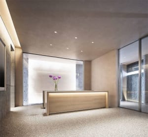 Modern reception desk with a wooden counter and a vase of purple flowers on top, set against a marble background.