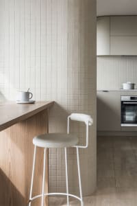A modern minimalist kitchen with a wooden island and white tile backsplash and floor.