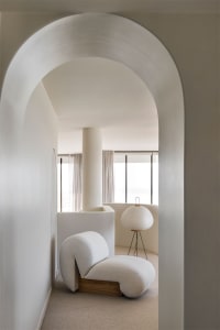 Modern, minimalist living room with white furniture and white lamp.