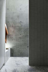 Modern industrial bathroom featuring concrete walls and marble floors.