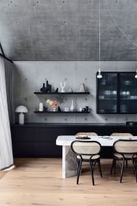 Minimalist dining room with a concrete wall, marble table, and black furniture.