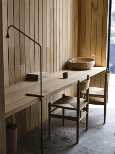 A modern study space featuring a wooden desk with a minimalist design, complemented by a woven basket and a sleek lamp.