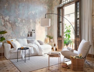 A serene modern bright living room with white fabric furniture, a large floor lamp, and a plant.
