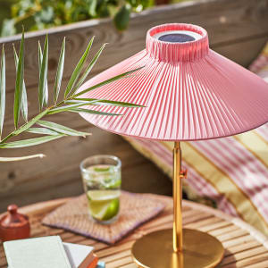 Pink paper lamp on wooden table with leaves and cocktail on glass